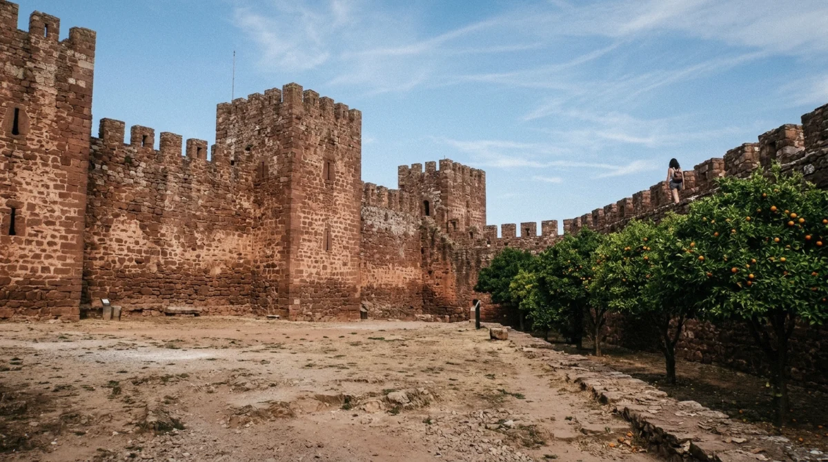 Red sandstone walls of the Moorish castle at Silves seen from the town below on a day trip, one of the inland things to do in Albufeira, Algarve